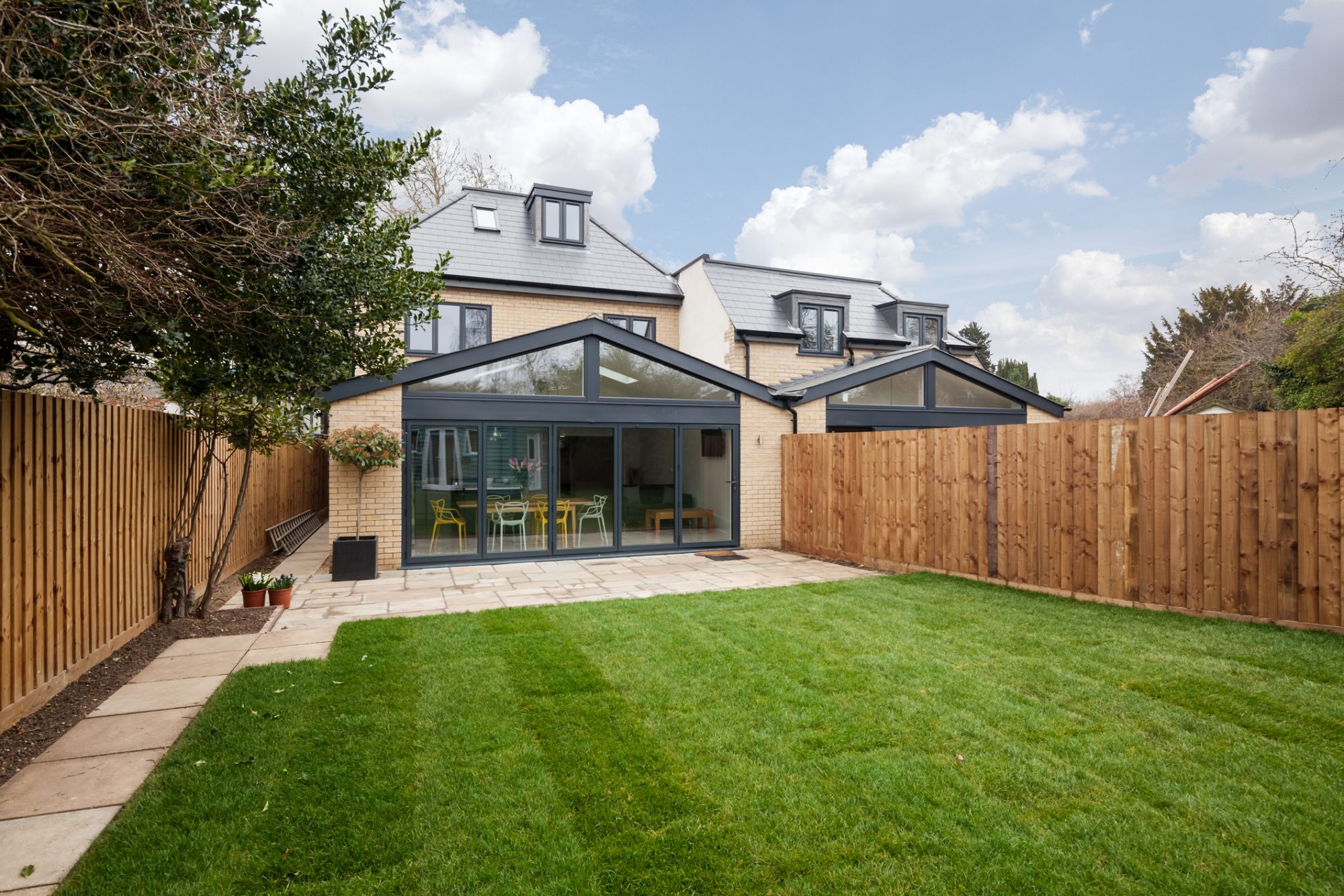 Highworth avenue, Cambridge, England - March 1 2019: Modern contemporary brick three storey suburban city home with Bifold patio doors and simple landscaped garden